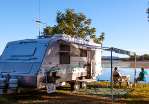 couple sitting by a caravan near lake